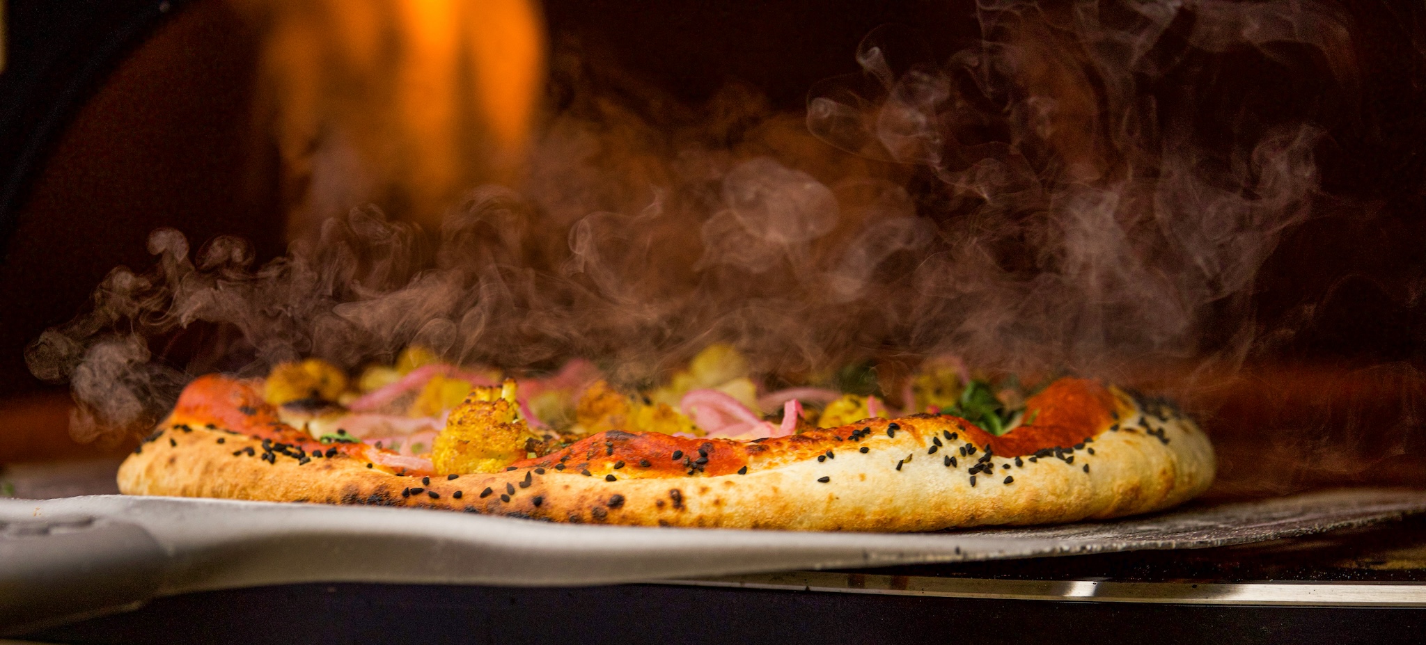 Fresh pizza coming out of the oven